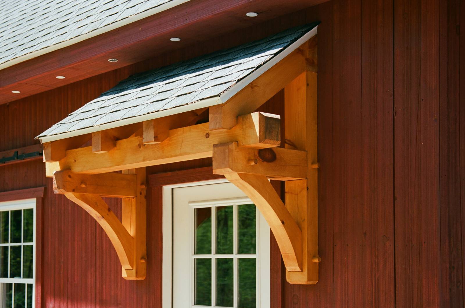 Timber frame eyebrow roof over the entry door