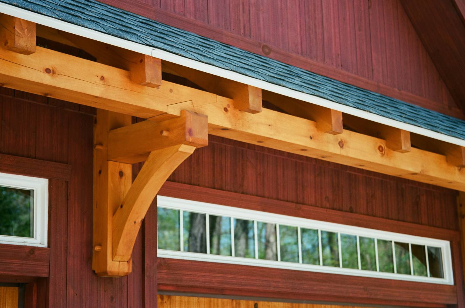 Timber frame eyebrow roof over the garage doors & transom windows