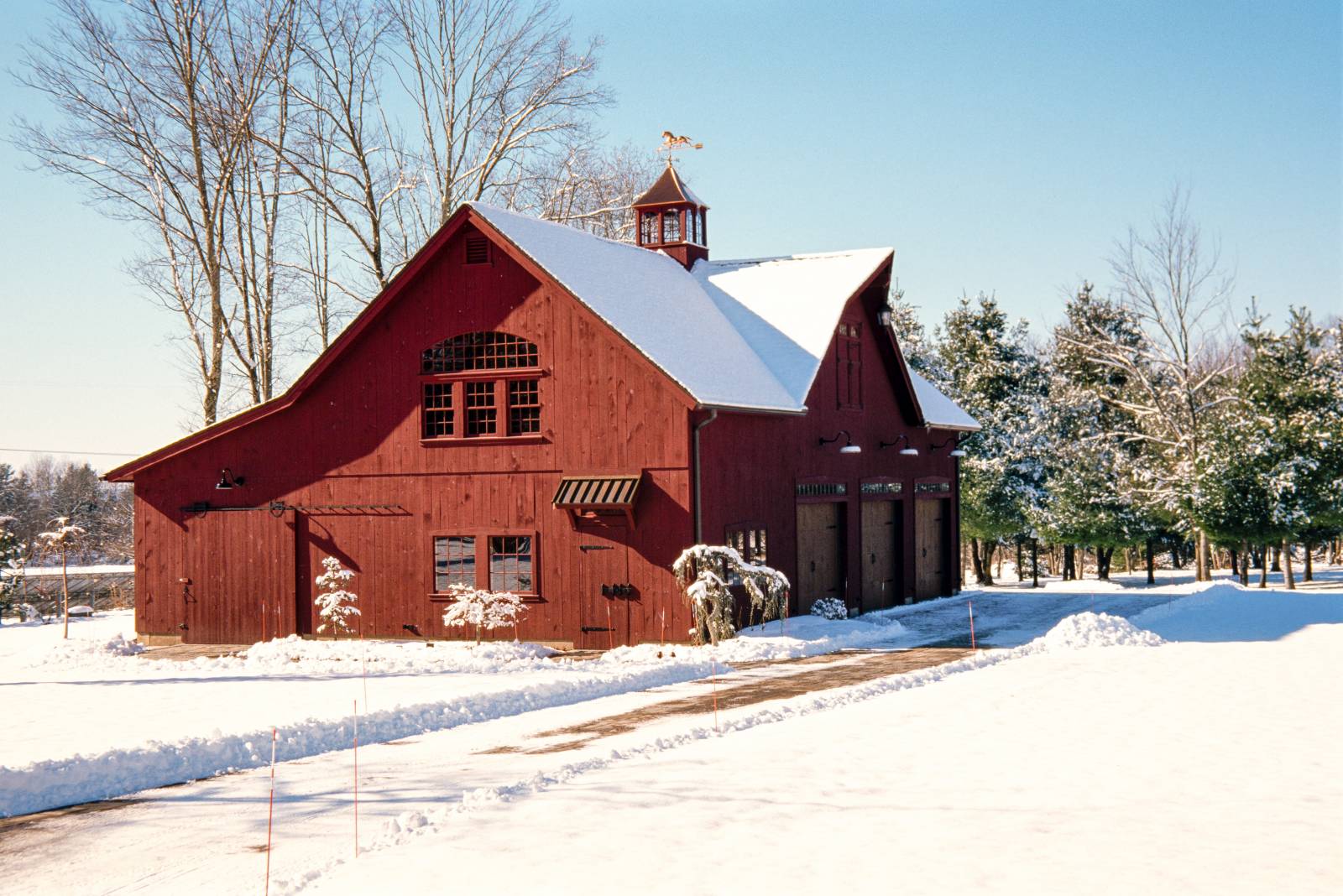 Plowed driveway leading to the red barn with an enclosed lean-to and reverse gable dormer