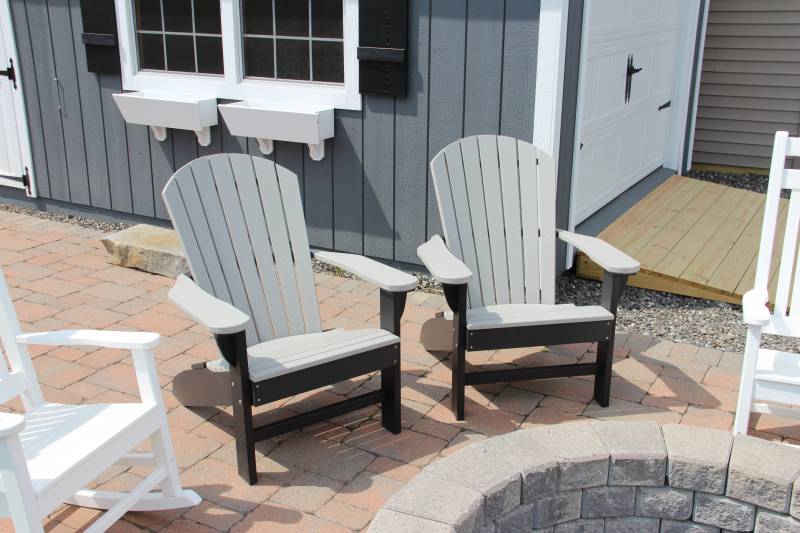 Two gray with black trim poly Adirondack chairs