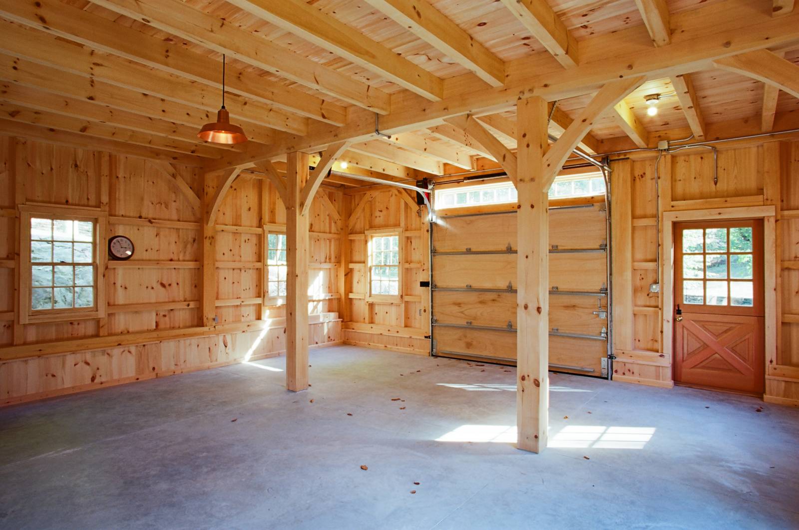 Downstairs in post & beam bank barn • pendant barn light • post & beam construction • authentic joinery • Dutch door • overhead door with wood panels