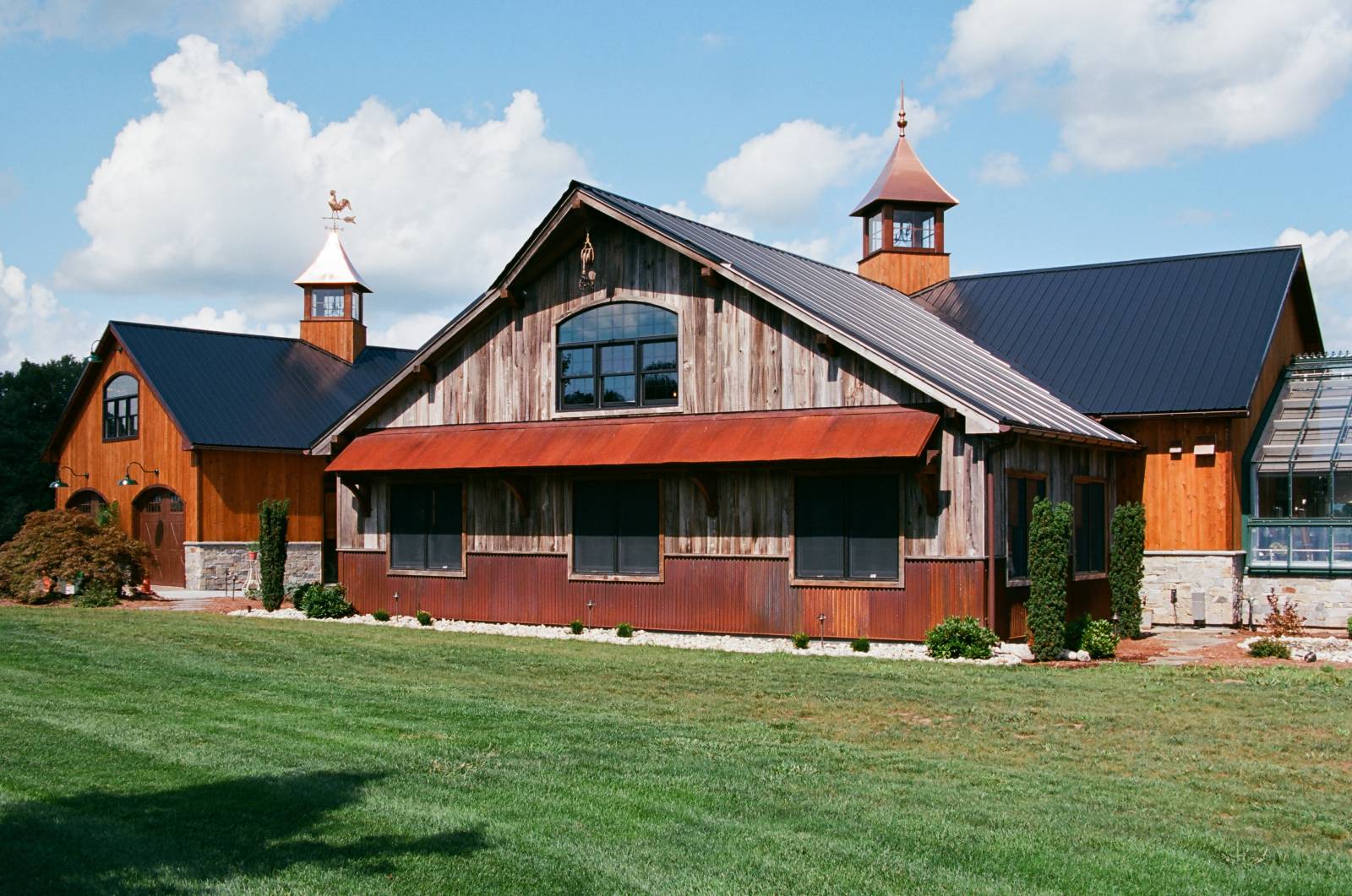 Reclaimed Barn Board Siding & Timber Frame Eyebrow Roof with Rusty Metal on Pool Room Exterior