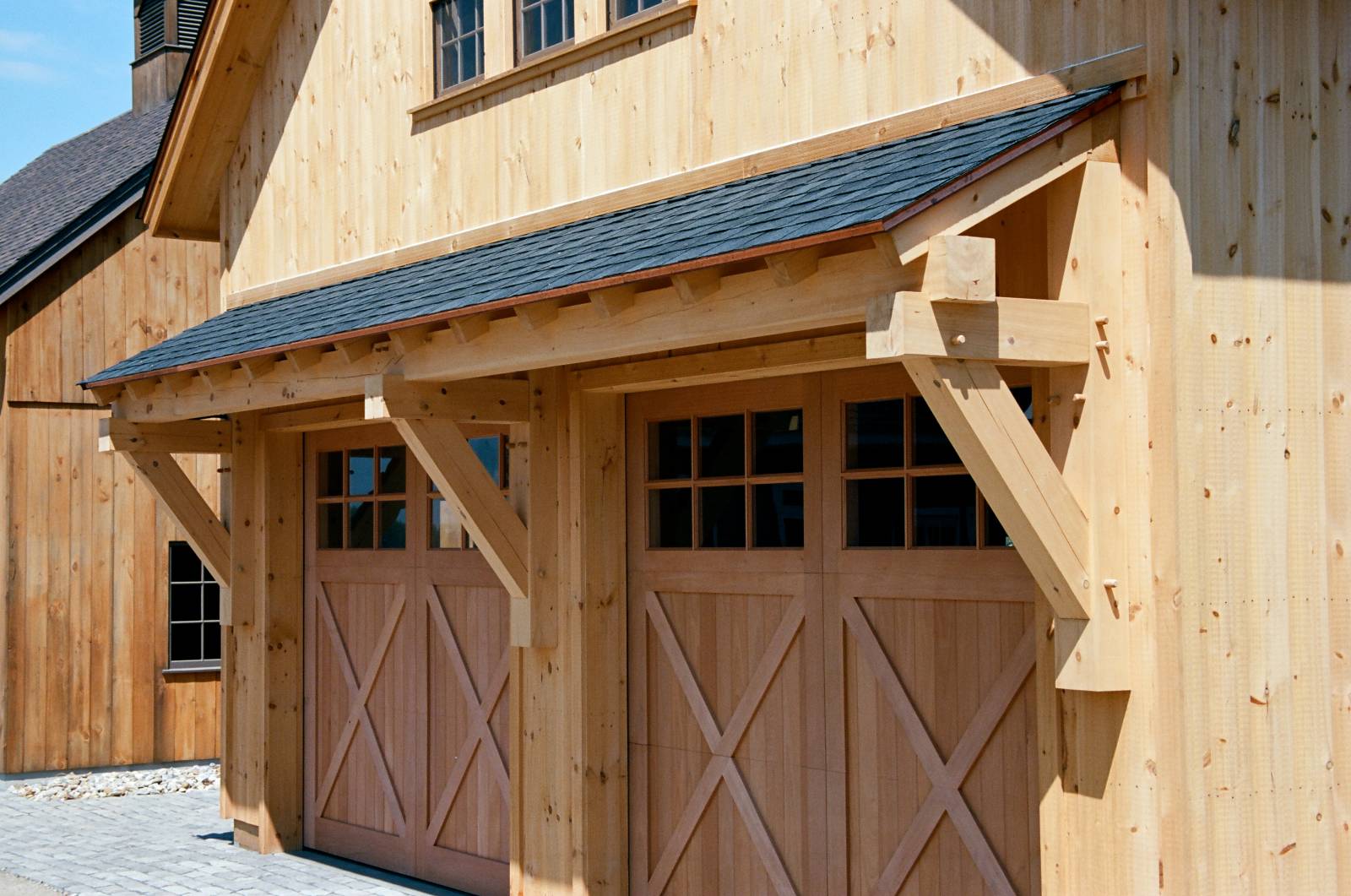24' Big Sky Timber Frame Eyebrow Roof over the Spanish Cedar overhead doors with square glass