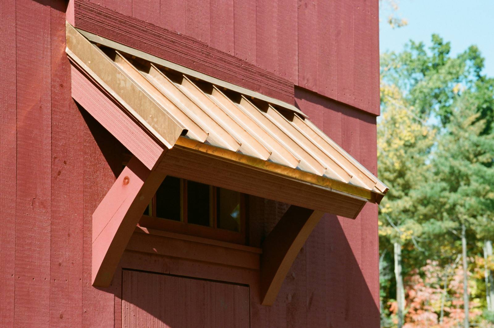 Custom Timber Frame Eyebrow Roof with Timbers Painted Red and Copper Standing Seam (on Carriage Barn)