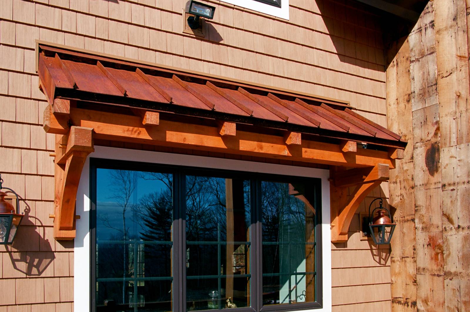 Timber Frame Eyebrow Roof with Rusty Standing Seam Roof on Custom Home