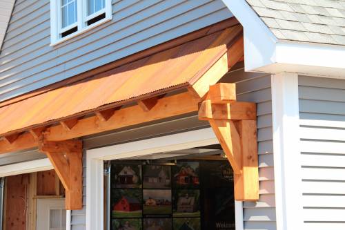 Timber Frame Eyebrow Roof over Garage Doors + Rustic Metal Roofing