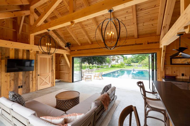 Timber Frame Pool House Interior with TV • Seating Area • Bar • Exposed Beams