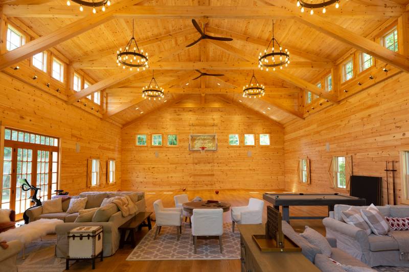 Inside the family barn with indoor basketball court • double transom dormers • timber trusses on the ceiling